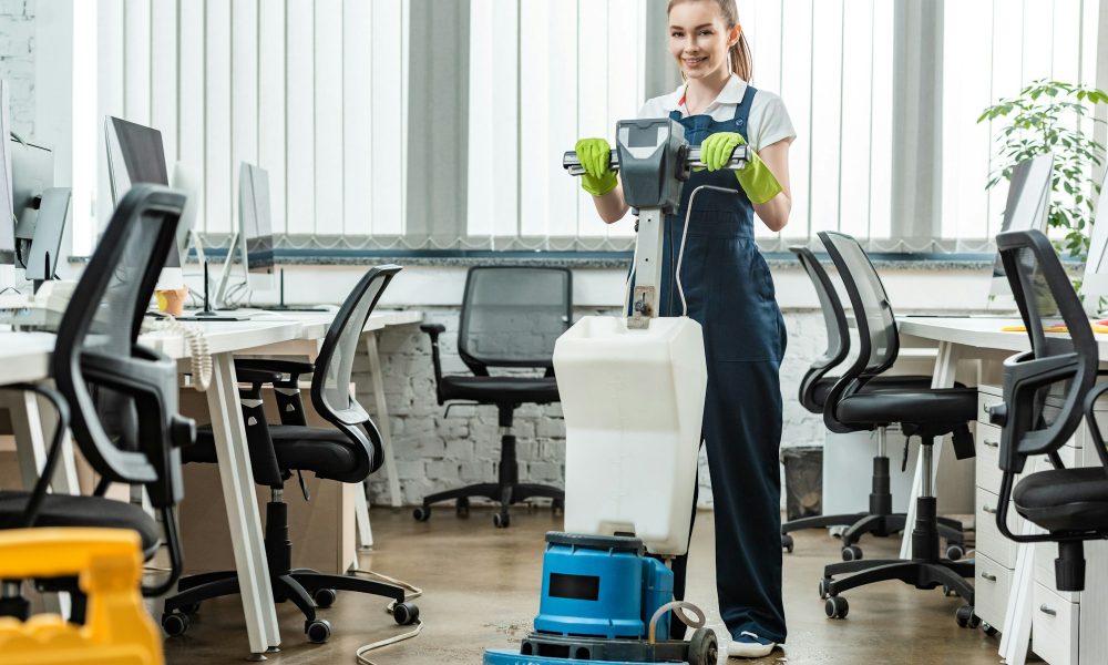 smiling cleaner washing floor in office with cleaning machine